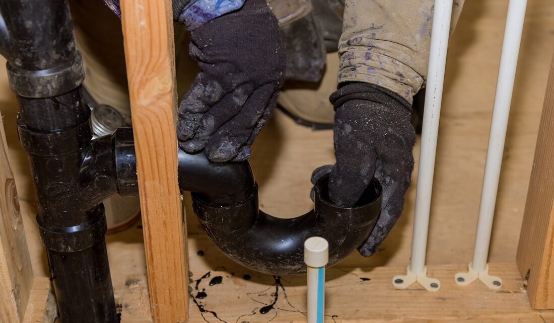 Worker is using glue with fitting for installing the PVC drain pipe in the work area.
