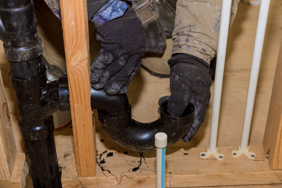 Worker is using glue with fitting for installing the PVC drain pipe in the work area.