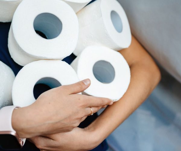 People are stocking up toilet paper for home quarantine from coronavirus. Woman holds many rolls of toilet paper